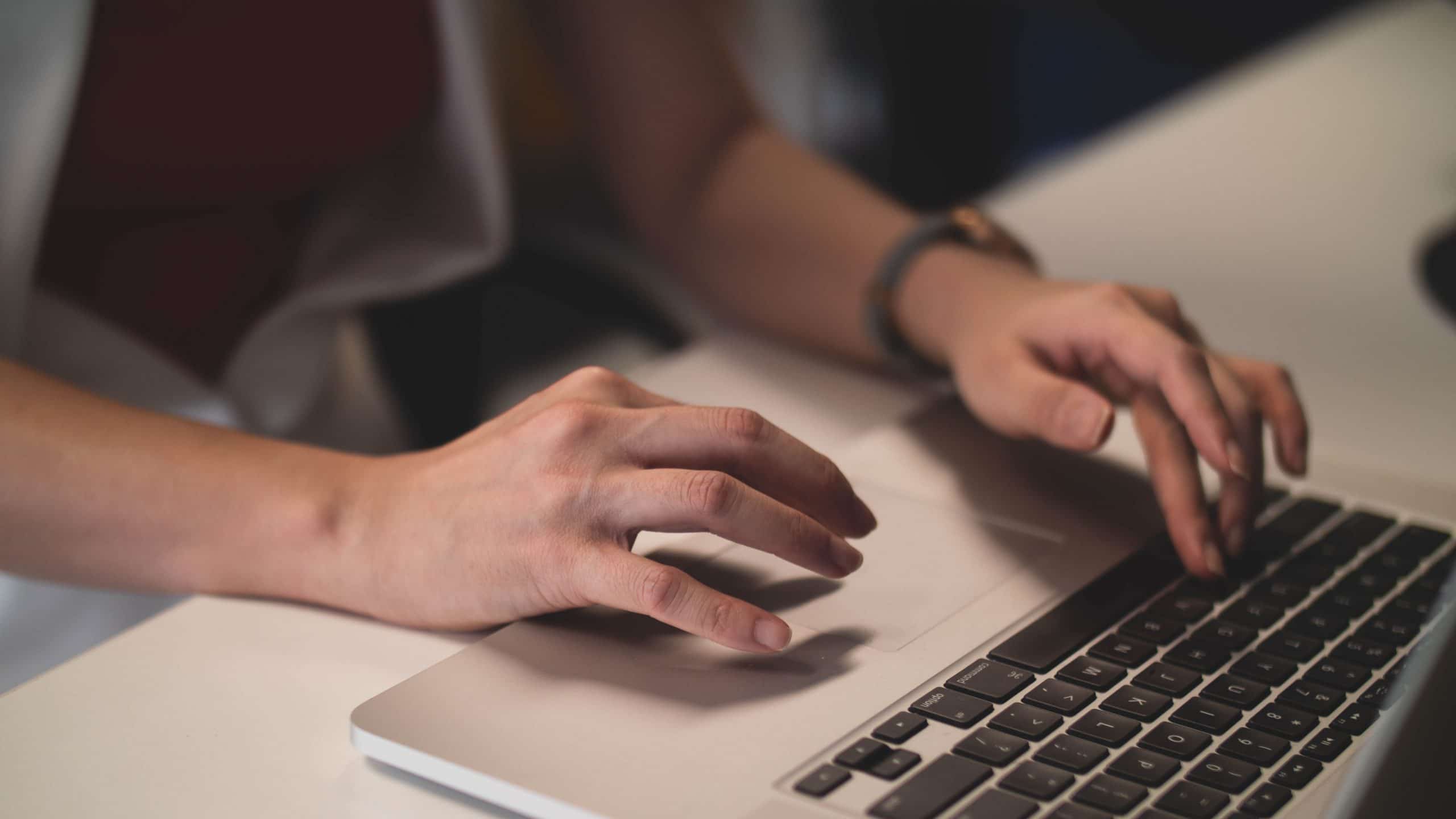A virtual assistant types on a laptop
